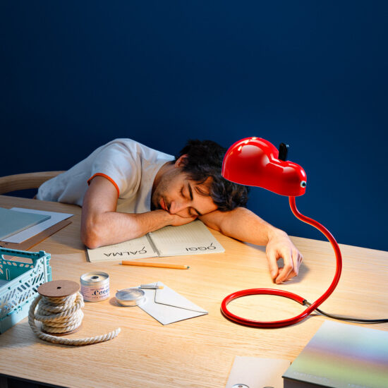 man slapend aan bureau met een rode stilnovo minitopo tafellamp
