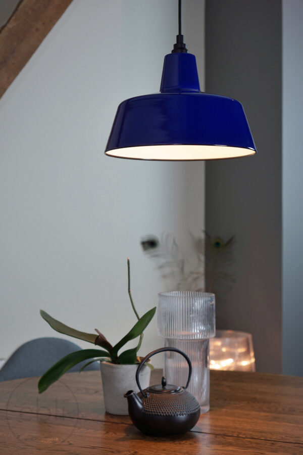Blauw emaille lamp boven ronde houten tafel