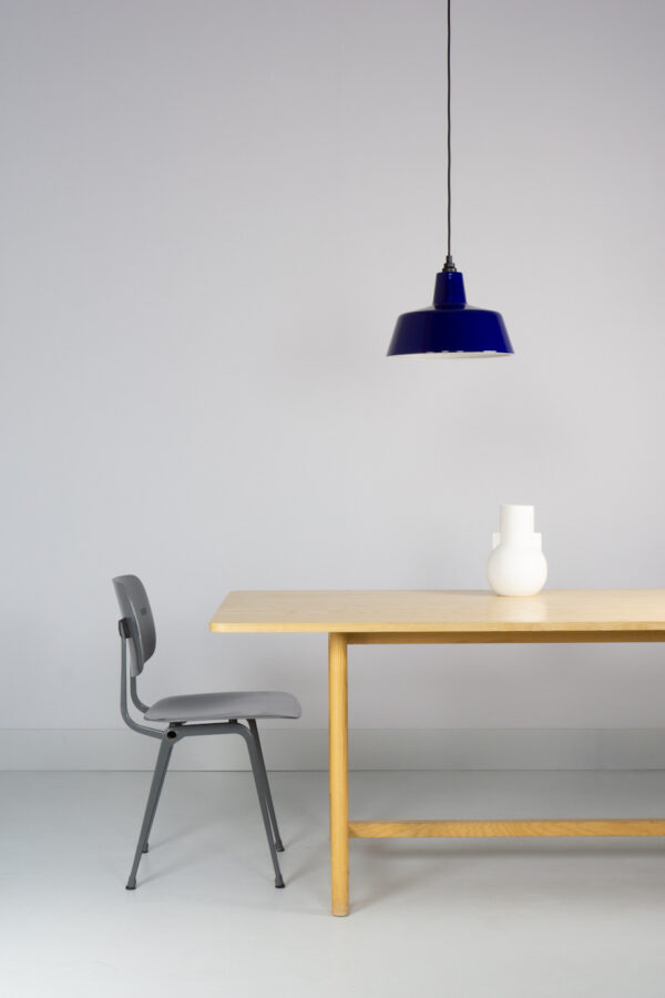 blauw emaille lamp van EBLI boven een HAY tafel