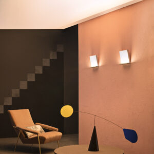 twee Stilnovo Inbilico wandlampen aan de muur in een kamer met tafel en stoel.