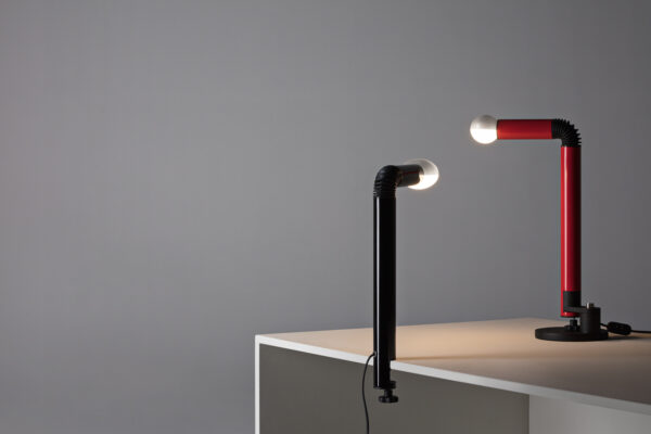 rode tafellamp en zwarte klemlamp Periscopio van Stilnovo op en aan een bureau